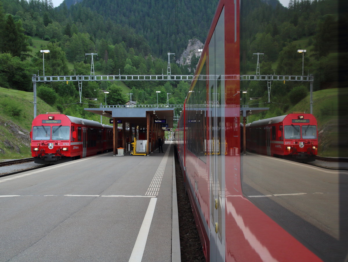 In einem Albula-Gliederzug spiegelt sich der zur Abfahrt bereitstehende Regio (Filisur - Davos Platz).

Filisur, 14. Juni 2017