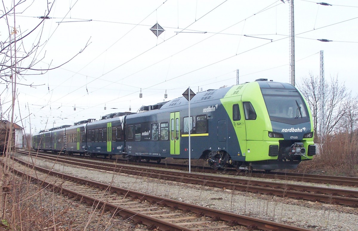 In Hennigsdorf liegt direkt neben dem S-Bahnsteig die Wagenübergabe zum Bombardier-Werk mit mehreren Aufstellgleisen. Diese werden aber auch von  Dritten  benutzt. Der hier angetroffene Flirt 3 ist natürlich von einem andern  bekannten Hersteller, der eine Montagestelle im benachbarten Velten hat und die Bombardier-Prüfstrecke gelegentlich  mit benutzt.
Dieser Flirt ist für die Nordbahn bestimmt, die ihrerseits für die Verkehrsverbünde in Hamburg und Schleswig -Holstein die Strecken Hamburg-Elmshorn nach Itzehoe und Wrist befahren wird. Aufgenommen am 13.12.14 in Hennigsdorf bei Berlin.