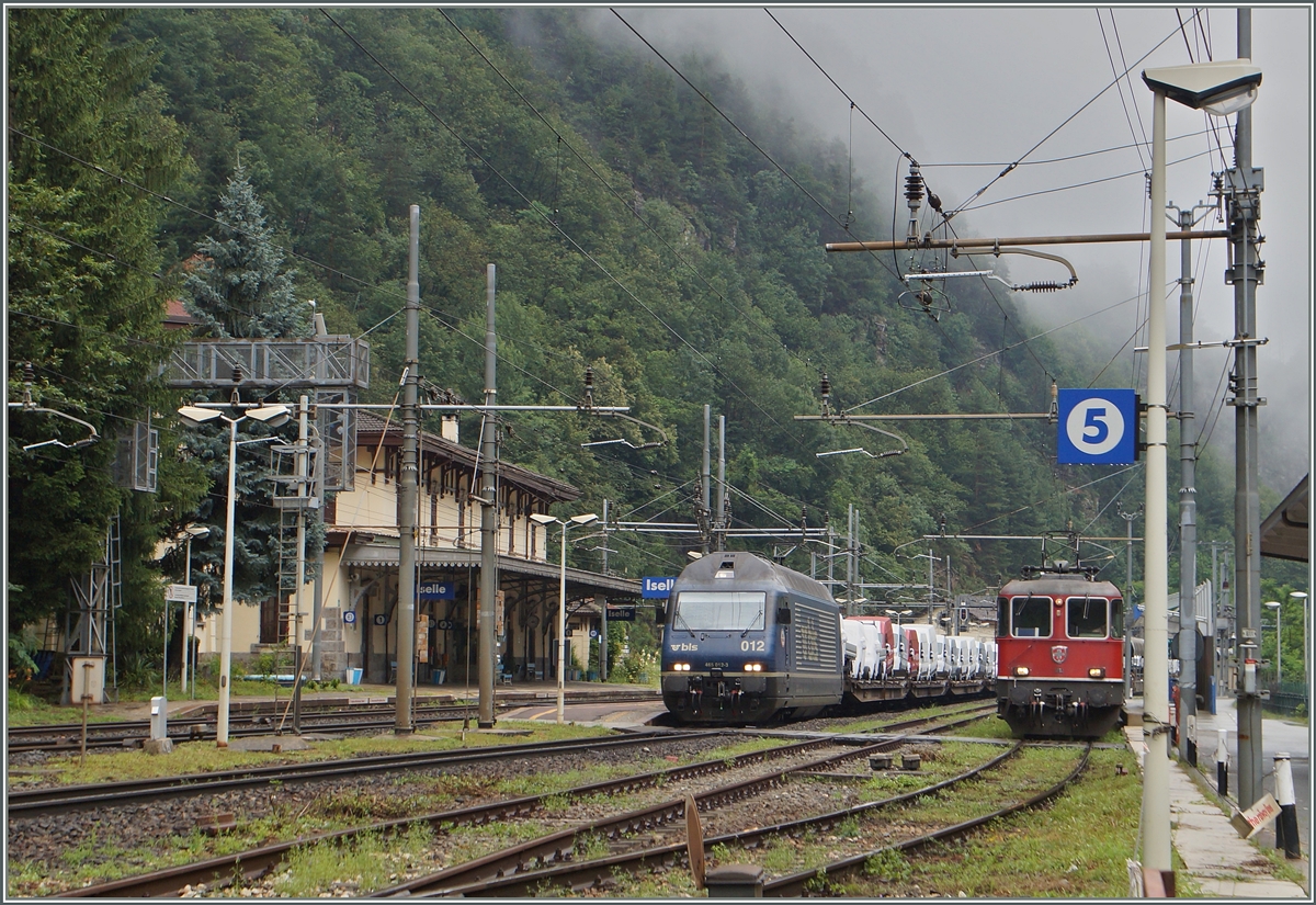 In Iselle wartet die SBB Re 4/4 II 11112 der Autozug 27972 auf die Abfahrt Richtung Brig, während die BLS Re 465 012 mit einem Zug farbrikneuer Auto durchfährt.
2. Juli 2014