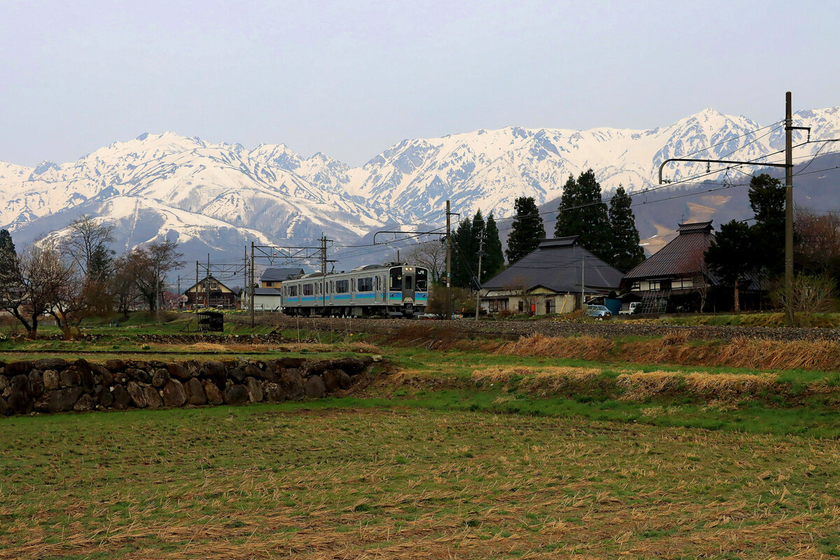 In den japanischen Alpen. Zweiwagenzug E127 No. 107 kommt früh am Morgen von Shinano Moriue her. 21.April 2022 