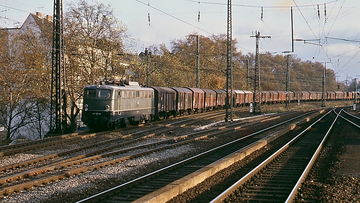 In Köln Süd ist 140 501-6 mit einem damals klassischen Güterzug unterwegs. Beim Vergleich mit aktuellen Aufnahmen wird deutlich, wie sehr sich das Bild der Güterzüge in der Zwischenzeit gewandelt hat.