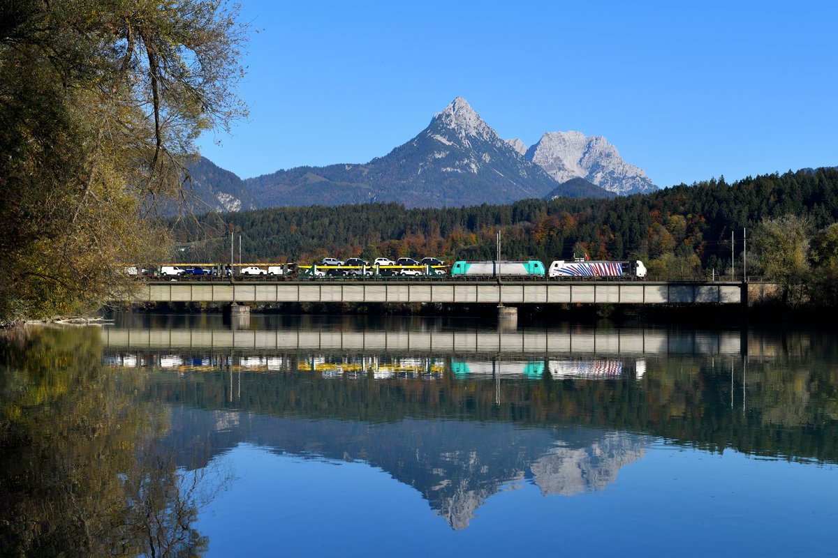 In Kufstein wurde der in München Nord gestartete Autotransportzug umgespannt. Nun beförderten 186 444 und 185 576 den als GAG 48865 bezeichneten Ganzzug zum Brenner. Nachdem der Inn an diesem schönen Herbsttag ruhig dahinfloss, konnte bei Langkampfen eine Aufnahme des Zuges samt Spiegelung umgesetzt werden. Im Hintergrund das imposante Kaisergebirge mit der Pyramidenspitze.  