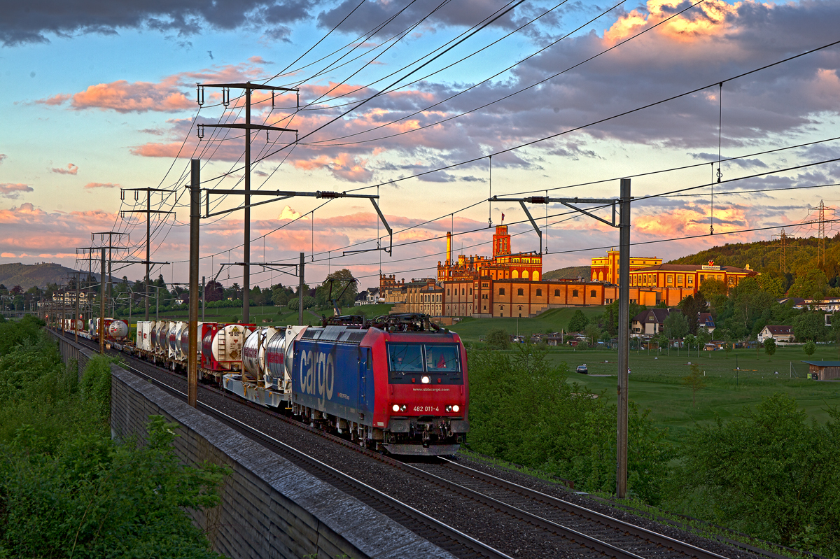 In den letzten Sonnenstrahlen erstrahlt die Brauerei Feldschlösschen als die 482 011-4 mit einem Wechselbehälterzug in Rheinfelden vorbeifährt.Bild vom 6.5.2015