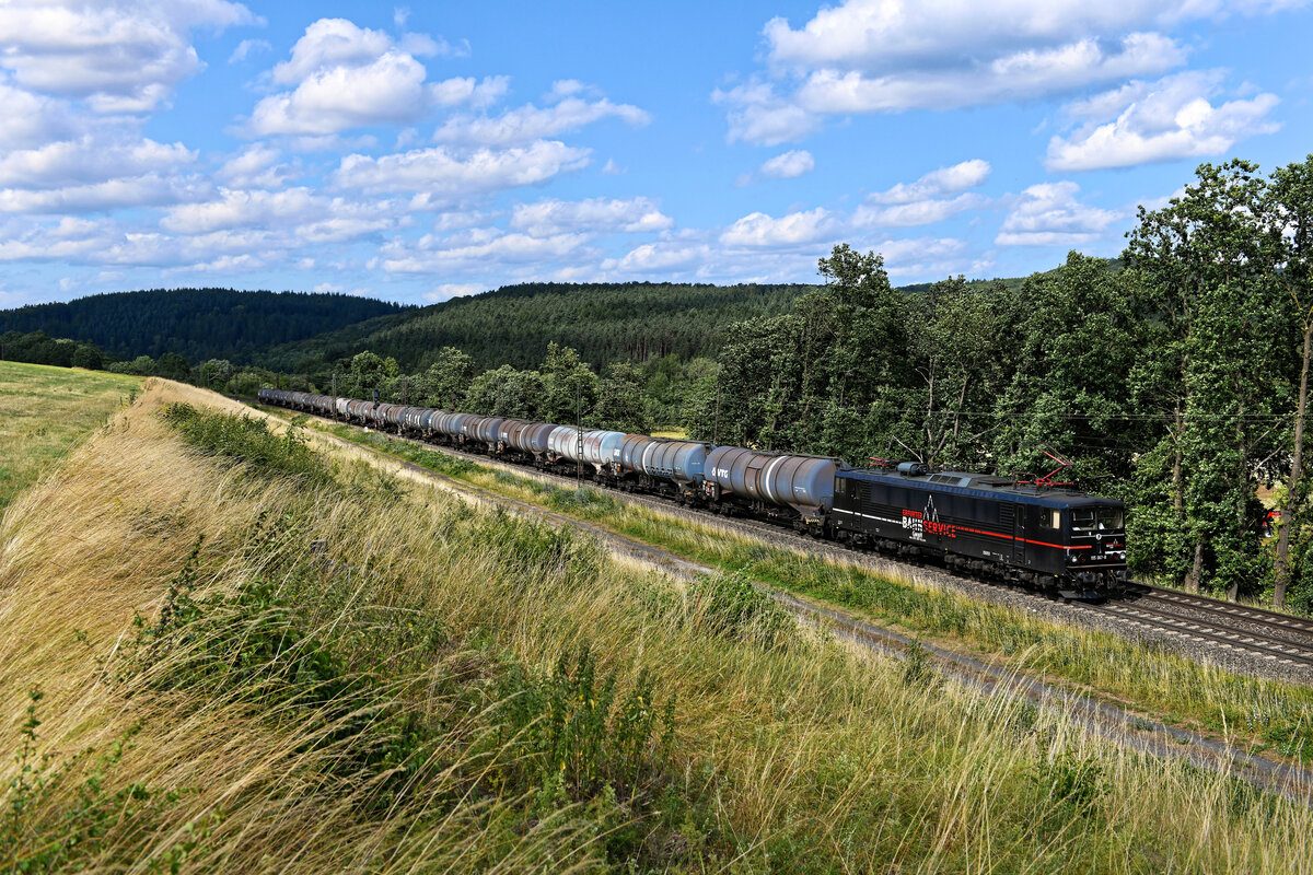 In der Nähe des Haune-Stausees bei Marbach in Osthessen konnte ich am 05. Juli 2023 die 155 007 der Erfurter Bahnservice GmbH mit einem Kesselwagenzug fotografieren. Die ganz in schwarz gehaltene Maschine war zum Aufnahmezeitpunkt im 47. Betriebsjahr und trug bereits die vierte Farbgebung seit sie 1977 die Werkshallen des VEB Lokomotivbau Elektrotechnische Werke „Hans Beimler“ in  Hennigsdorf verlassen hat.  