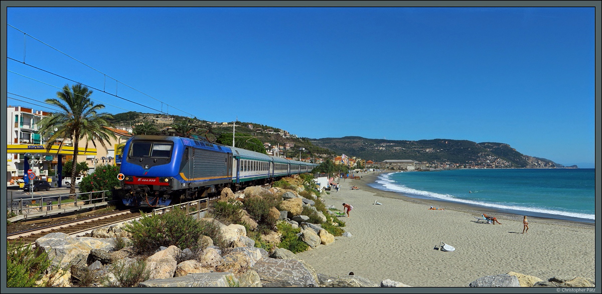 In Pietra Ligure führt die Strecke Genua - Ventimiglia direkt am Strand entlang. Der Abschnitt ist einer der wenigen, die noch nicht ins Landesinnere verlegt wurden. Bei strahlenden Sonnenschein zieht E.464 539 am 25.09.2018 den R 11346 weitgehend unbeachtet von den wenigen Badegästen nach Ventimiglia.