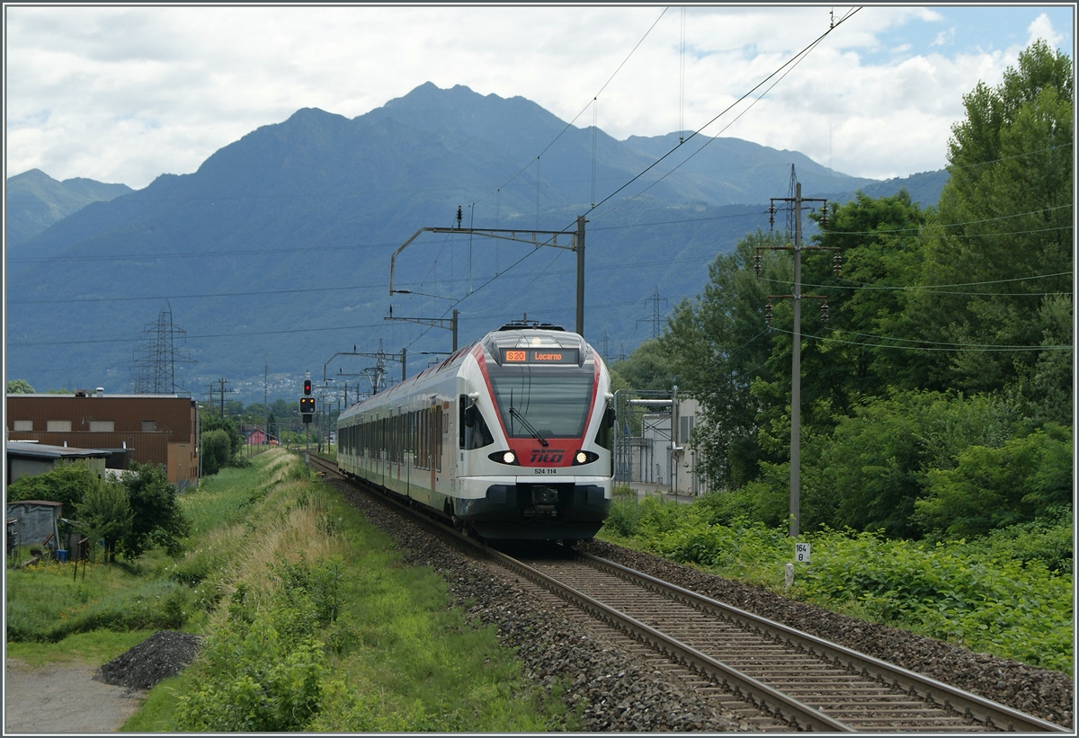 In Riazzino wurde der  Bahnhof  als Haltestelle gut einen Kilometer nach Westen verlegt; doch der ursprüngliche Bahnhof dient weiterhin als Kreuzungsstation der S20 TILO. das Bild entstand am Bahnsteigende der Haltestelle und zeigt neben dem ankommenden RABe 524 114 im Hintergrund die Lage des  alten Bahnhofes .
21. Juni 2015
