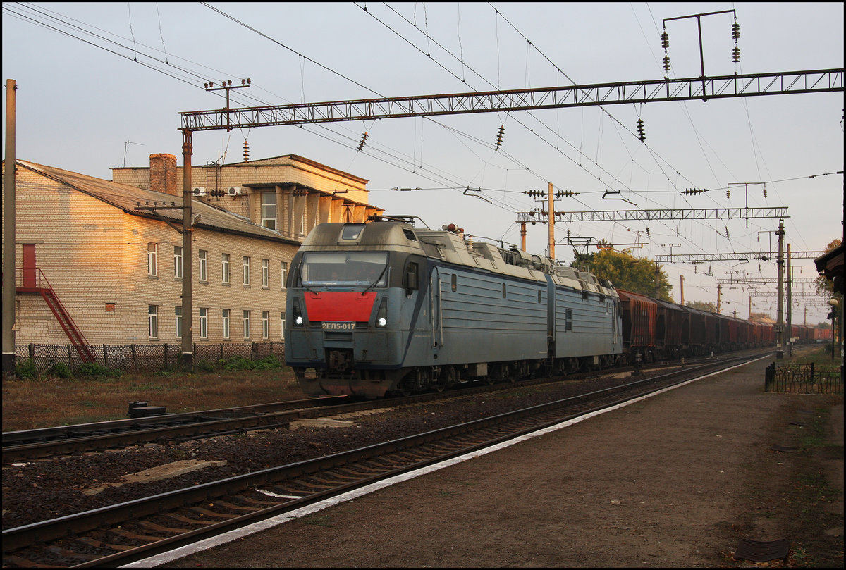 In Rudnitsa treffen die Hauptstrecke Odessa - Lviv - Kiev mit der ca. 7o km langen Schmalspurbahn von Hajvoron zusammen. Während auf der Schmalspurstrecke nur wenige Personenzüge verkehren, herrscht auf der Hauptbahn reger Güter- und Personenzugverkehr. Hier kommt am Morgen des 11.10.2016 eine modernisierte Doppellok der Reihe 2 EL 5-017 mit ihrem Güterzug aus Richtung Odessa durch den Bahnhof.