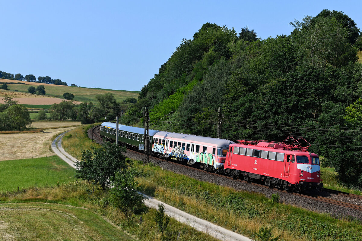 In einer Sichtungsgruppe wurde am Vormittag des 09. Juli 2023 eine  rote Ost-Lok  bei Fulda nordwärts fahrend gemeldet. Umso erstaunter war ich, als sich diese bei der Durchfahrt in Hermannspiegel dann als die orientrote 110 459 der GfF aus Crailsheim entpuppte. Eine schöne Überraschung, auch wenn der Anhang - bestehend aus einem  Karlsruher Kopf  und zwei grünen n-Wagen - wenig fotogen war. Über die farbliche Gestaltung der Maschine kann man geteilter Meinung sein. Mir hat die orientrote Farbgebung auf kaum einer Lok gefallen. Dennoch finde ich es gut, dass zumindest eine der noch im Einsatz stehenden  Bügelfalten  auch an diese Epoche erinnert. Interessanterweise hat die 110 459 zu Zeiten ihres Einsatzes bei der DB nie diese Lackierungs-Variante getragen.  