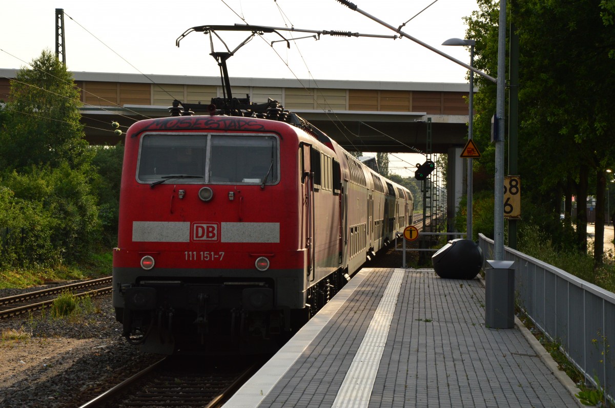 Ins Gegenlicht fährt die 111 151-7 schiebend einen RE4 durch Korschenbroich gen Aachen Hbf, in wenigen Minuten wird sie den Zug in Mönchengladbach Hbf einschieben. 7.7.2015
