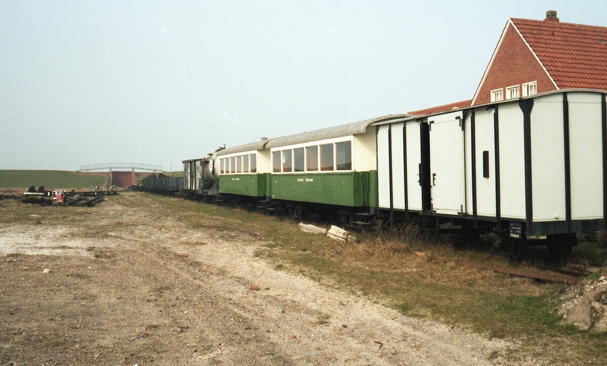 Inselbahn Spiekeroog__April 1984. Inselbahn GmP, zusammengestellt für den Abtransport : offene und gedeckte G-Wagen ex OEG, Heizöl-Kesselwagen 32 und die P-Wagen 12+13 ex MEG Zell-Todtnau, im (ehemaligen) Bahnhofsgelände.
