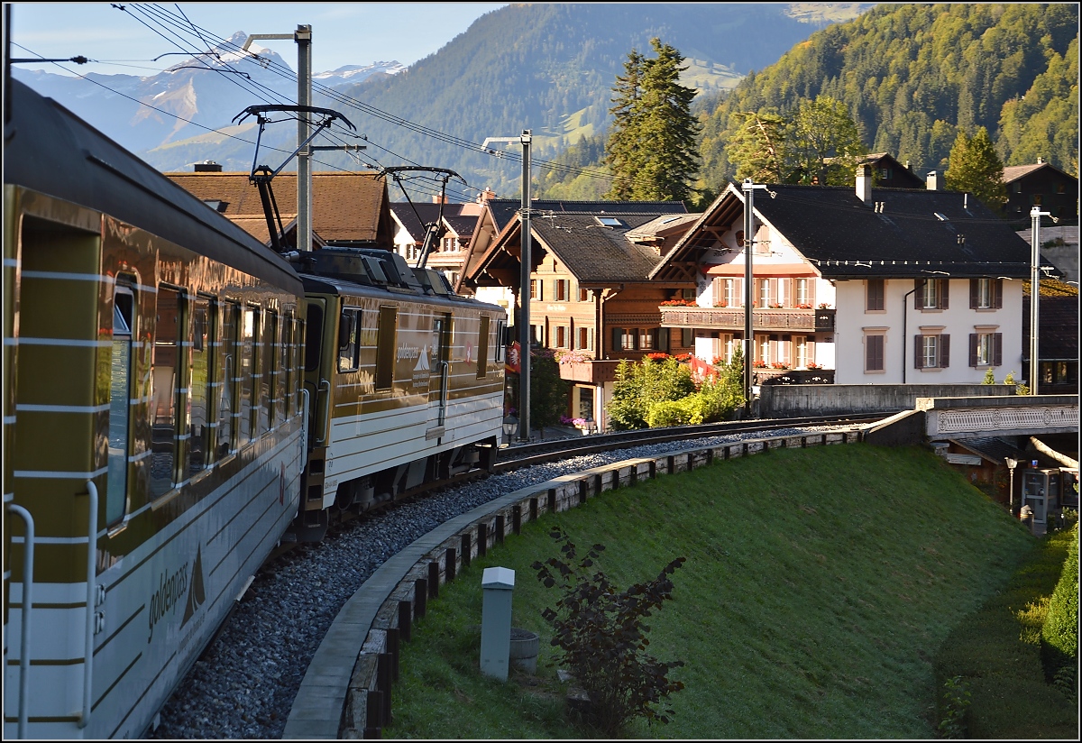 Interessante Fahrt der MOB im Schlepptau von Gepäcktriebwagen GDe 4/4 6005. Einfahrt nach Gstaad mit Blick auf die Hauptstraße. September 2014.