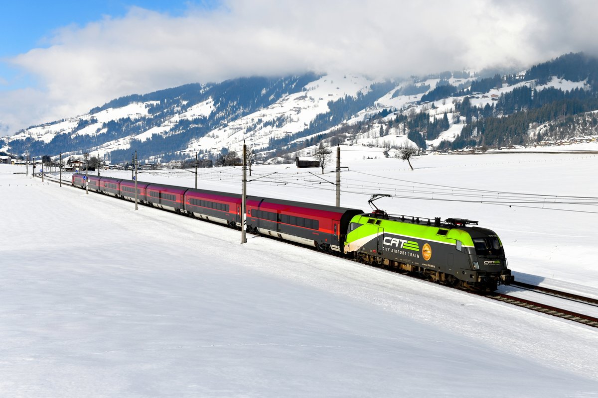 Inzwischen können Railjets auch planmäßig auf der Salzburg-Tiroler-Bahn beobachtet werden, dies allerdings nur an bestimmten Verkehrstagen. Am 23. Februar 2019 war der RJX 1265 von Wörgl nach Wien Flughafen eingelegt. Ersatzweise kam an diesem Tage die 1016.036 - eine Lok des City Airport Trains mit entsprechender Lackierung - zum Einsatz. Bei Durchfahrt des Zuges gab es erfreulicherweise eine Wolkenlücke und der rare Einsatz eines CAT-Taurus vor einer Railjet-Garnitur konnte in Sonne dokumentiert werden. 