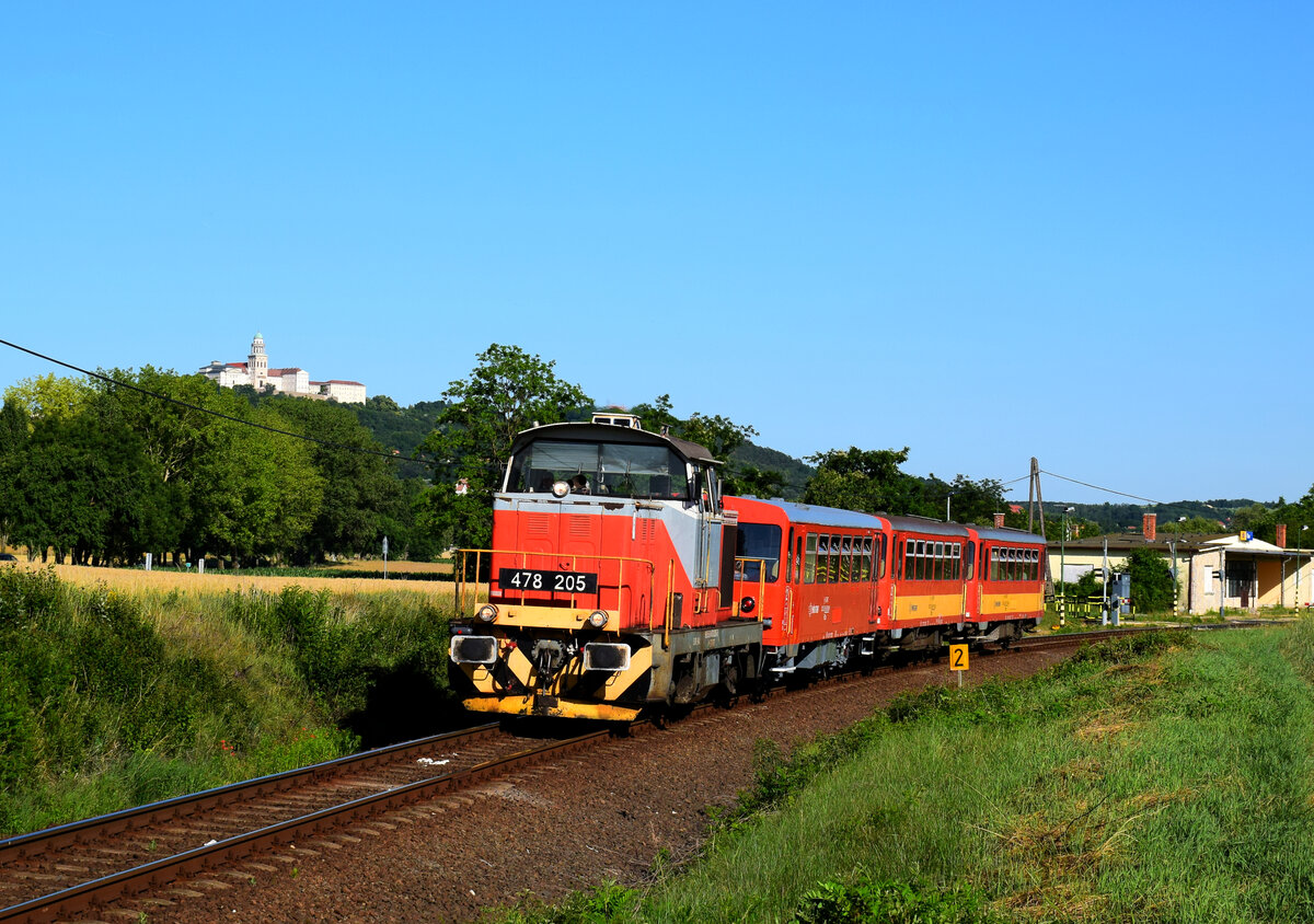 Ist wieder Sommer: sind wieder die MÁV-Start Verschubloks im Personenzug-Einsatz in Ungarn.
Die 478 205 mit dem Zug 39513 (Die Zuggarnitur sind aus Bzmot Beiwagen) kurz nach der ehemalige Hst. Écs. Kann man auch die Benedikterabtei von Pannonhalma im Hintergrund zu sehen.
Écs, 18.06.2022.