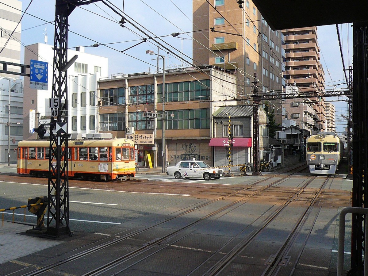 Iyo-Bahn, in der Stadt Matsuyama: Kreuzung von Zug 3502 mit der Strassenbahn von Matsuyama. Der Strassenbahnwagen 2003 stammt von der stillgelegten Strassenbahn Kyôto und gelangte 1979 hierher. 18.September 2009. 