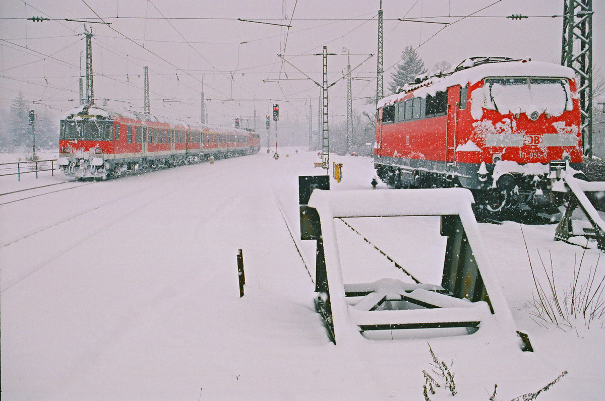 Jahreszeitgemäß gibt's heute noch mal eine Schippe Schnee auf die Mütze: Am 25. Januar 2004 im Bahnhof Freilassing. Ein Nahverkehrszug fährt nach Salzburg. 111 055 wartet auf den nächsten Einsatz.