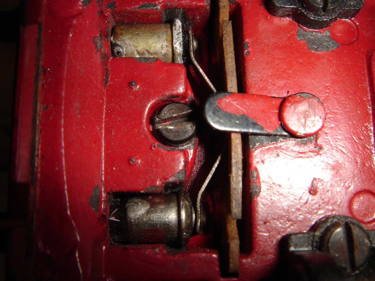 Jetzt endlich, nach dem Abbau beider Vorlaufgestelle, liegen die Gehäusebefestigungsschrauben der TP 800.1 frei und können gelöst und entfernt werden - hier die vordere. In diesem Zustand lassen sich auch die Steckbirnchen auswechseln, indem man den kleinen Riegel, der die Anfeder- und Kontaktplatte in Position hält, zu Seite dreht und diese Platte nach unten herauszieht, soweit das Stromkabel es erlaubt. Die Birnchen können dann mit einer Pinzette gegriffen und entfernt werden. Der kleine Riegel, von dem die Rede ist, ist bei dieser Version am Chassis angenietet, Bei späteren Versionen geschraubt, was natürlich den Riegel sicherer in Position hält als die hier gezeigte Lösung. Aufnahme 28.09.2014