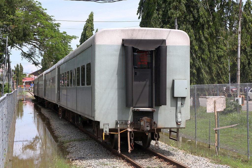 JKNS 8906-D als letztes Fahrzeug des PU502 (Beaufort - Sembulan) am 10.Februar 2025 gleich nach der EK beim Km 90,0 in Beaufort. - Links des Zuges erkennt man noch die Reste der Überflutung wegen der der Zugsverkehr einige Tage vorher in diesem Abschnitt eingestellt war.