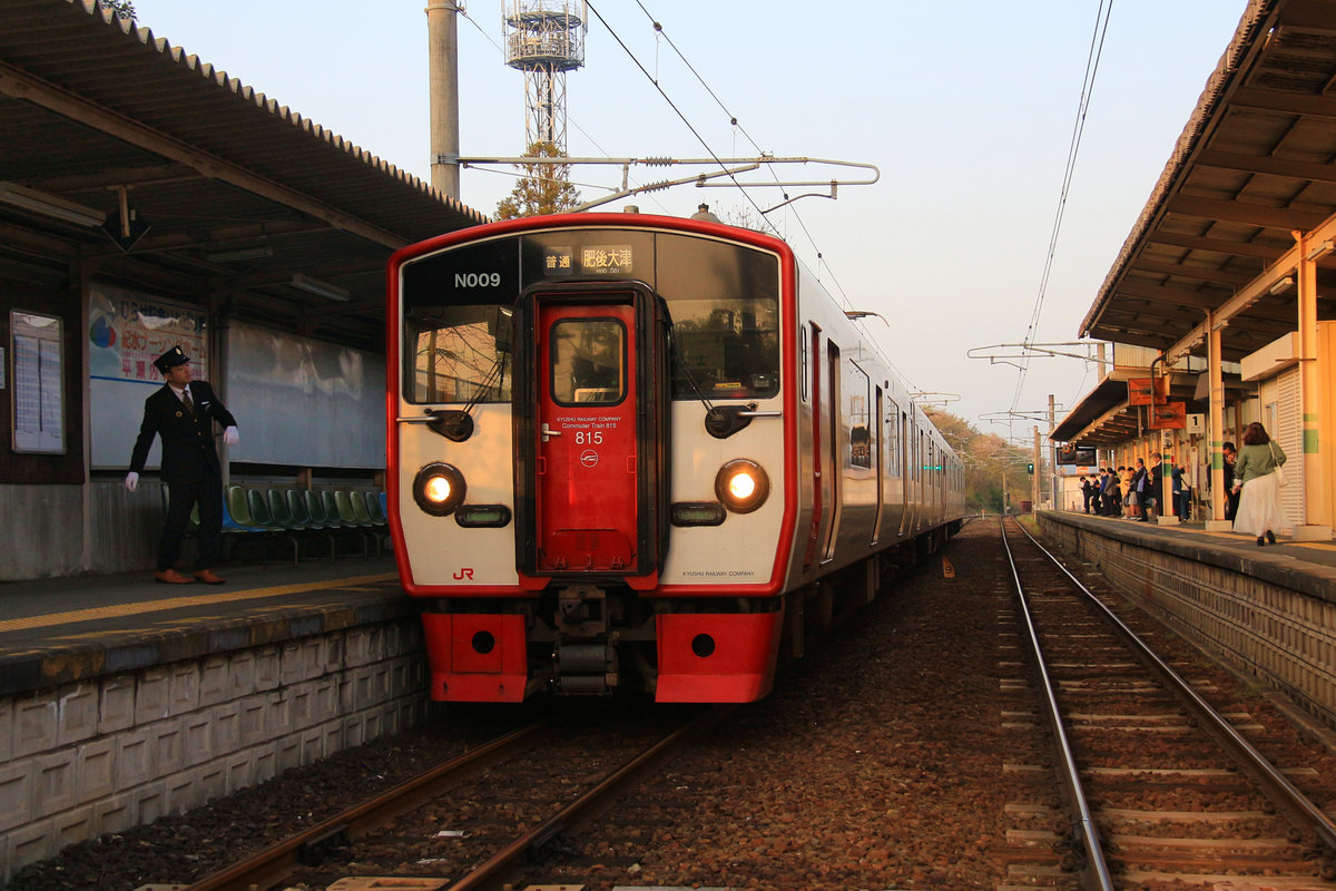 JR Kyûshû Serie 815: Es ist noch früh am Morgen, und dem Wagenführer ist noch etwas schläfrig. Während sein Zug (815 Nr.9) auf einen Gegenzug wartet, steigt der Wagenführer deshalb aus und macht auf dem Bahnsteig heftige Gymnastikübungen. Musashizuka, 2.April 2018 