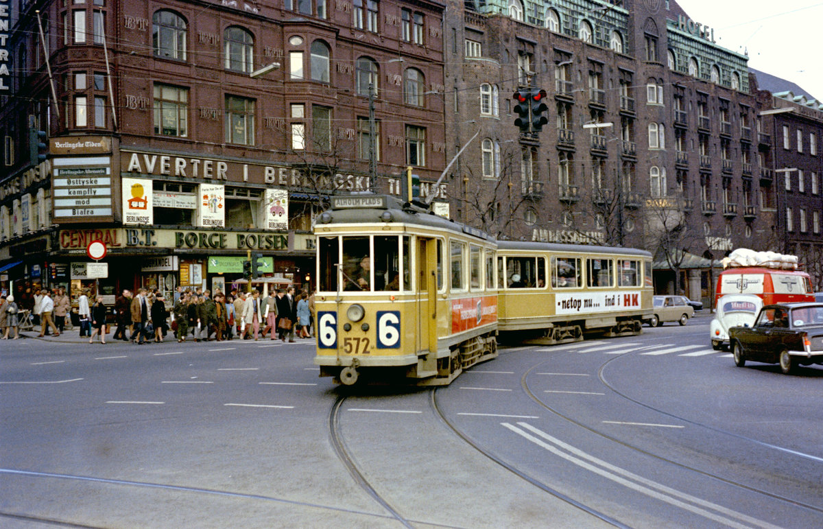 København / Kopenhagen Københavns Sporveje SL 6 (Tw 572 + Bw 15**) København V, Stadtzentrum, Vester Voldgade / Frederiksberggade / Rådhuspladsen am 11. April 1969. - Die Frederiksberggade bildet mit den Straßen Nygade und Vimmelskaftet, dem Amagertorv und der Østergade eine etwa 1,1 km lange zusammenhängende Hauptgeschäftsstraße, die man in Kopenhagen  Strøget  (: Strecke) nennt. Diese Hauptgeschäftsstraße, die vom Rådhuspladsen bis zum Kongens Nytorv läuft, wurde 1962 als die damals längste Fußgängerstraße der Welt geöffnet. - An der Mauer des Gebäudes an der Straßenecke steht in einem  Aushängeschild  der  Berlingske Aftenavis  (diese Zeitung heißt heute  Weekendavisen ), dass  ostdeutsche, dh. DDR-, Kampfflugzeuge gegen Biafra  (entweder schon verwendet werden oder später zum Einsatz kommen werden - das ist nicht unmittelbar ersichtlich, was der genaue Sinn ist - und ich habe das nicht näher untersucht!). - Scan eines Farbnegativs. Film: Kodak Kodacolor X.