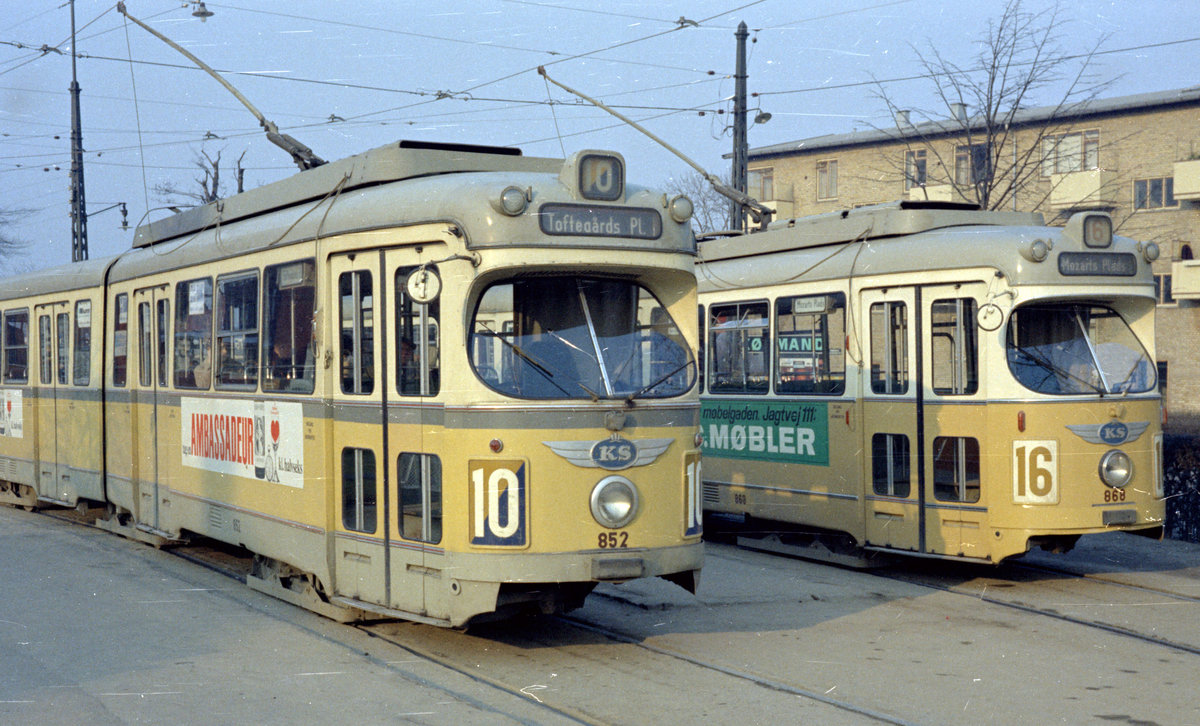 København / Kopenhagen Københavns Sporveje (KS): Zwei  Düsseldorfer , der DÜWAG-GT6 852 als SL 10 und der DÜWAG-GT6 868 als SL 16, halten eines Tages im April 1968 in der Endstellenwendeschleife am Emdrupvej. - Die beiden Gelenktriebwagen gehörten zur Serie 801 - 900, welche die KS von DÜWAG/Kiepe in den Jahren 1960 bis 1968 empfing. Die Wagen 851 - 852, 858 - 862 und 877 - 900 wurden von der KS-Hauptwerkstätte fertig gebaut. - Emdrup war früher ein Dorf. Der Name hängt wahrscheinlich mit dem mittelalterlichen Männernamen Imbre oder Imbri zusammen, jedenfalls benennt eine schriftliche Quelle von 1393 den Ort 'Imbresthorp'. Das Wort 'thorp' bedeutete im Mittelalter einen  Aussiedlerort , d.h. ein Ort, wo Bauern ihre Höfe aus den Dörfern aufs freie Feld verlegt hatten, und so bedeutet Emdrup wohl ursprünglich den Ort, wo sich der Aussiedler Imbre niedergelassen hat. - Das Suffix '-thorp' (etymologisch mit dem deutschen 'Dorf' verwandt) findet man in vielen dänischen Ortsnamen, die die Endsilbe '-drup','-rup', '-trup' und '-terp' haben. - Scan von einem Farbnegativ. Film: Kodacolor X.