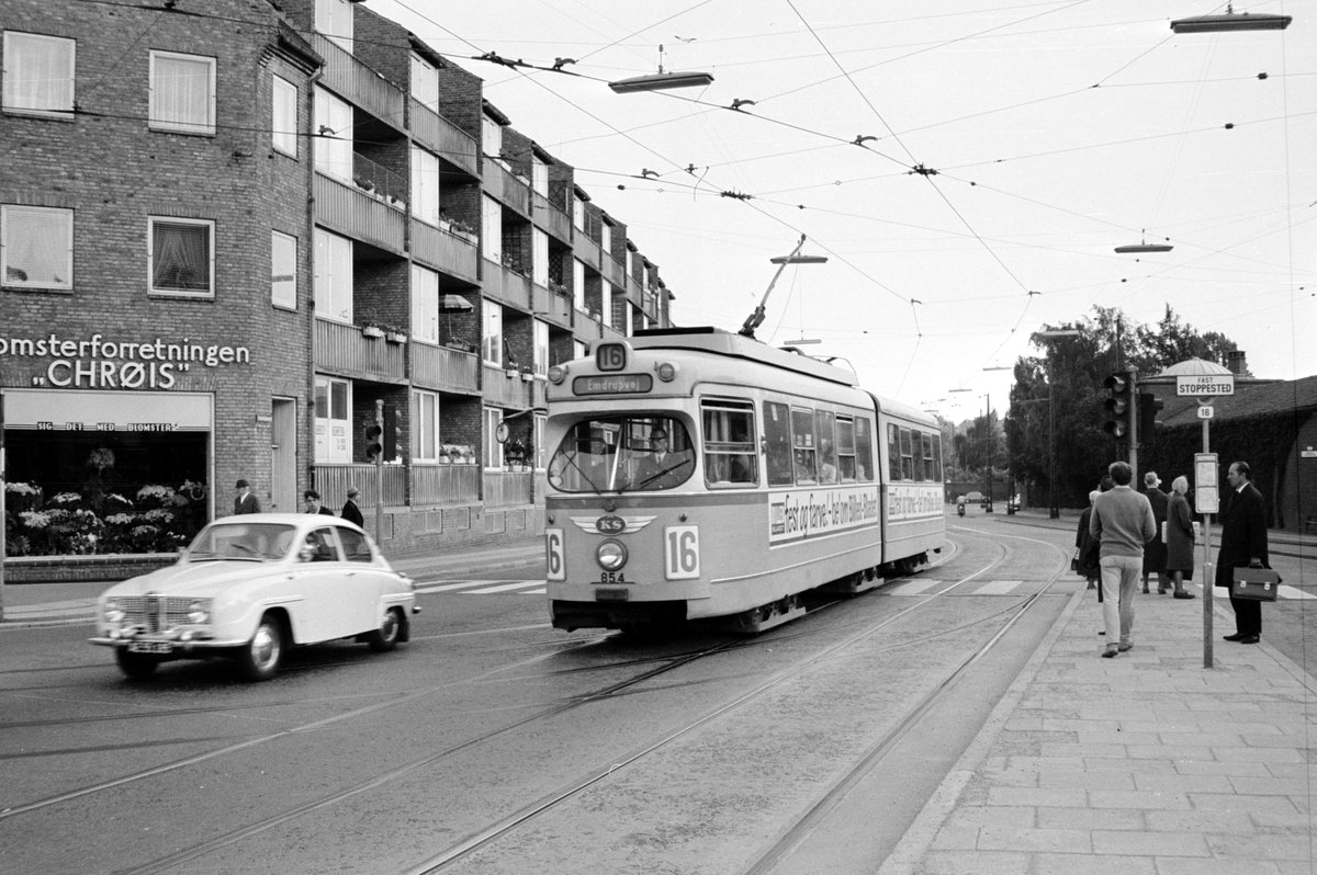 København / Kopenhagen Københavns Sporveje SL 16 (DÜWAG-GT6 854) Bispebjerg (København NV), Frederiksborgvej / Tagensvej / Bispebjerg Torv im Juni 1968. - An der Haltestellentafel der SL 16 steht 'FAST STOPPESTED' (: obligatorische Haltestelle). Haltestellen, an denen es z. B. Umsteigemöglichkeiten gab, waren 'fast' (: obligatorisch; das dänische Eigenschaftswort 'fast' bedeutet eigentlich 'fest'); hier sollte die Straßenbahn immer halten. An den anderen Haltestellen, die nur den Text 'STOPPESTED' hatten, musste nur gehalten werden, wenn es Fahrgäste gab, die aus- oder einsteigen wollten. - Scan von einem S/W-Negativ. Film: Ilford FP3.