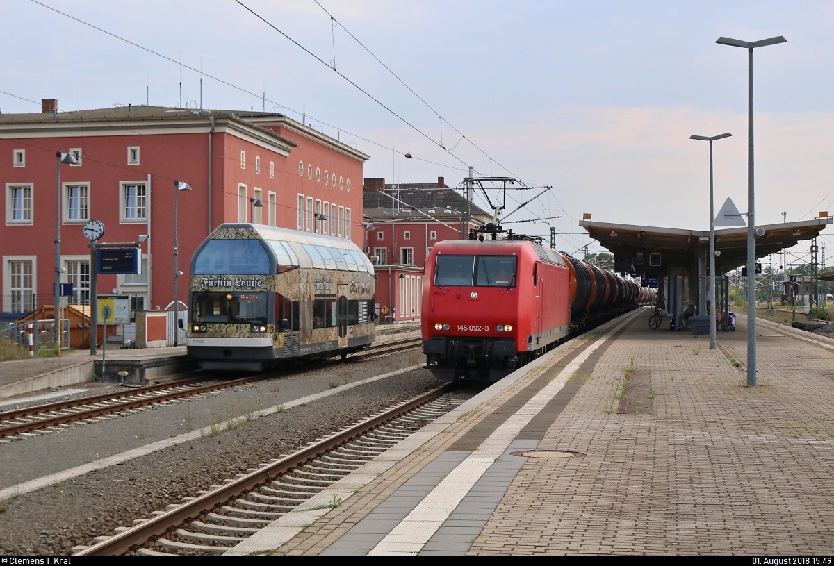 Kesselzug mit 145 092-3 der Beacon Rail Leasing Ltd., vermietet an die HSL Logistik GmbH, durchfährt Dessau Hbf auf Gleis 2 in nördlicher Richtung, vorbei an 670 003-2  Fürstin Louise  der Dessauer Verkehrs- und Eisenbahngesellschaft (DVE) als DWE75712 nach Wörlitz.
[1.8.2018 | 15:49 Uhr]