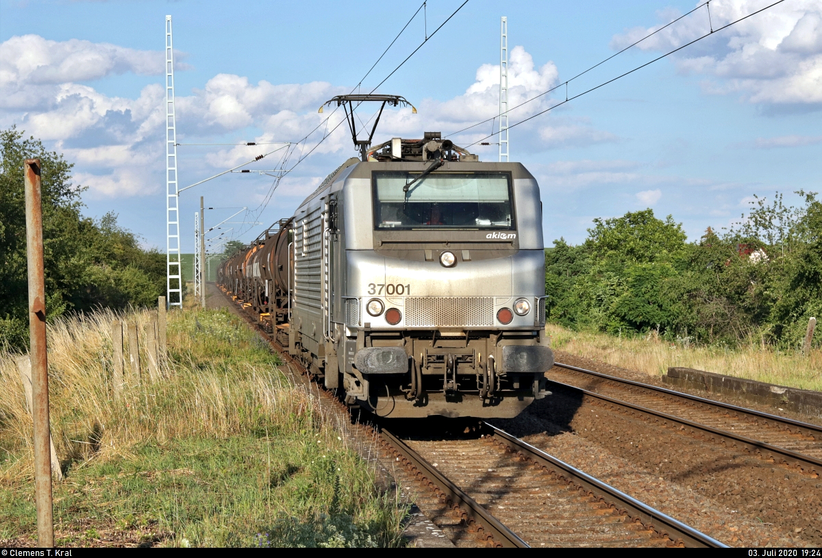 Kesselzug mit BB 37001 (91 87 0037 001-1 F-AKIEM | Alstom Prima EL3U/4) der Akiem S.A.S., aktueller Mieter unbekannt, durchfährt den Hp Teutschenthal Ost auf der Bahnstrecke Halle–Hann. Münden (KBS 590) Richtung Teutschenthal.
Bereits eine Woche zuvor ist mir diese Lok zur fast selben Zeit begegnet.
Aufgenommen am Ende des Bahnsteigs 2.
[3.7.2020 | 19:24 Uhr]