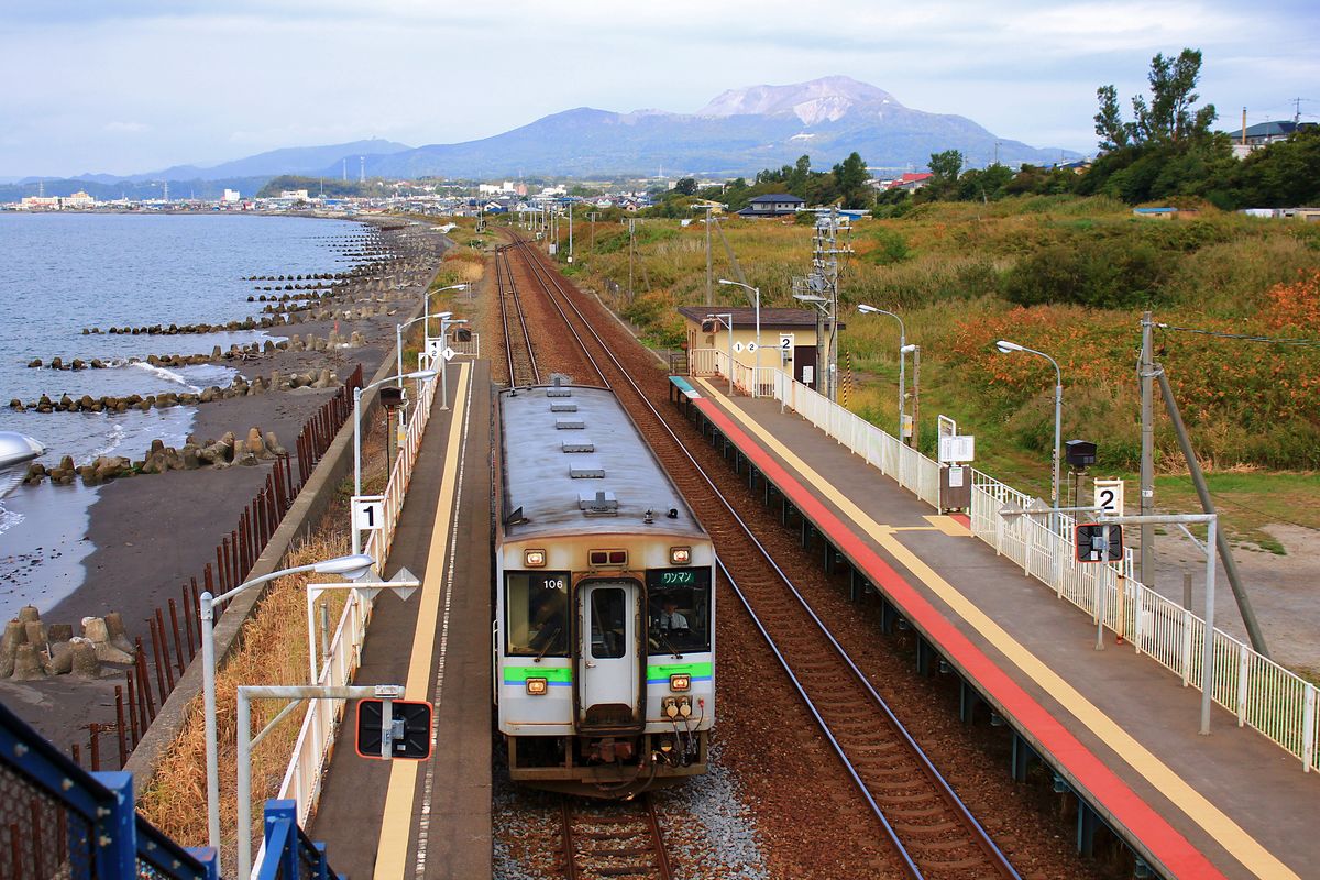 KIHA 150 (キハ150) von JR Hokkaidô: KIHA 150-106 in Kita Funaoka an der  Bucht der Vulkanausbrüche  an der Südküste von Hokkaidô. Im Hintergrund der Vulkan Ususan, an dessen gewaltige Eruptionen 1977 und 2000 mit Schaudern zurückgedacht wird. 28.September 2014. MURORAN-HAUPTLINIE 