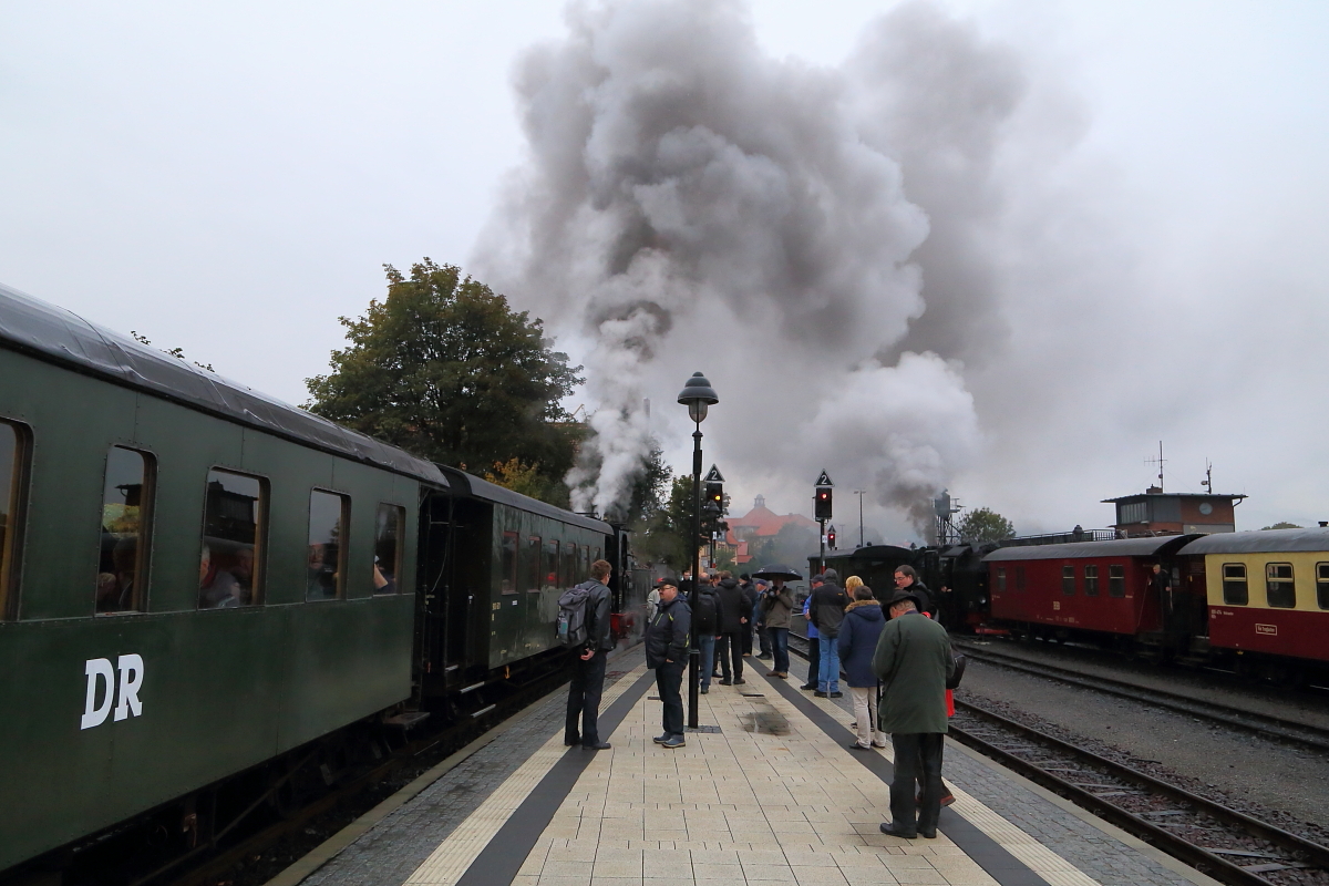 Kleine Szene am Morgen des 17.10.2015 im Bahnhof Wernigerode. Während sich auf dem Bahnsteig langsam die Fahrgäste des links auf Gleis 34 stehenden IG HSB-Sonderzuges einfinden, machen zwei Loks bereits mächtig Dampf. Vor dem Sonderzug ist es Mallet 99 5901, welche in wenigen Minuten nach Nordhausen Nord fahren wird und rechts eine Neubaudampflok der Reihe 99 72 mit Planzug P 8931, welche dem Sonderzug 10 Minuten später mit Fahrziel Brocken folgt.