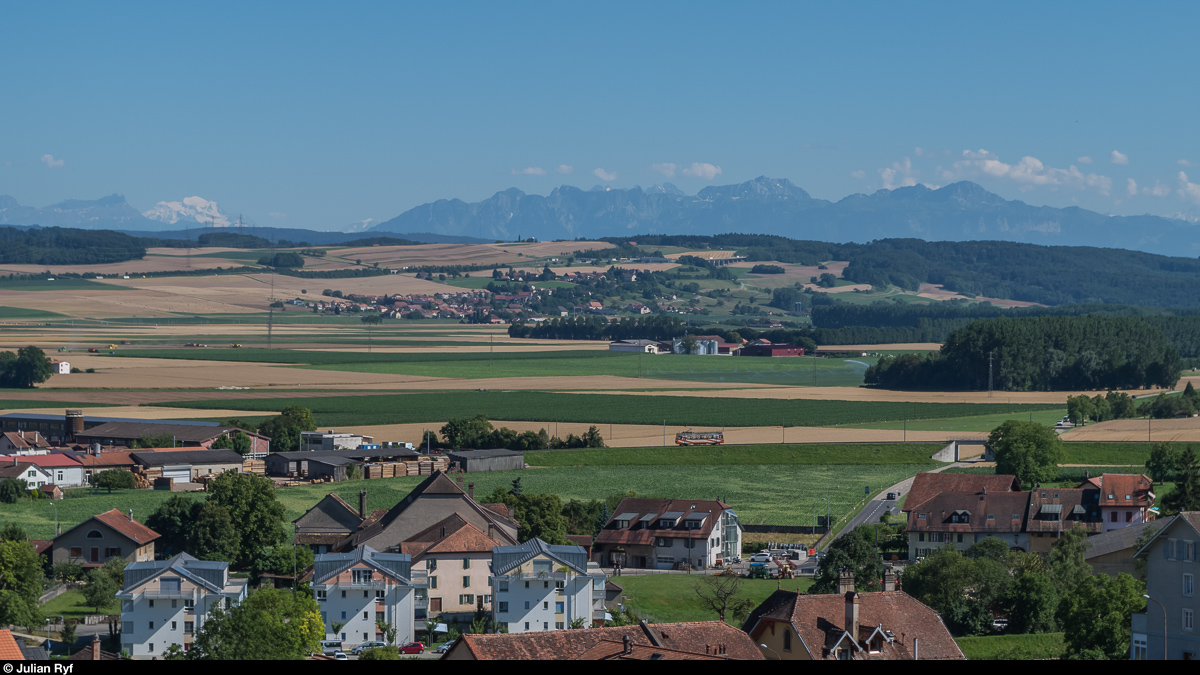 Kleiner Zug noch kleiner. Der Be 2/2 14 der zu Travys gehörenden Orbe-Chavornay-Bahn erklimmt am 19. Juli 2016 zwischen den Haltestellen Les Granges und Saint Eloi die Rampe zum Städtchen Orbe hinauf.