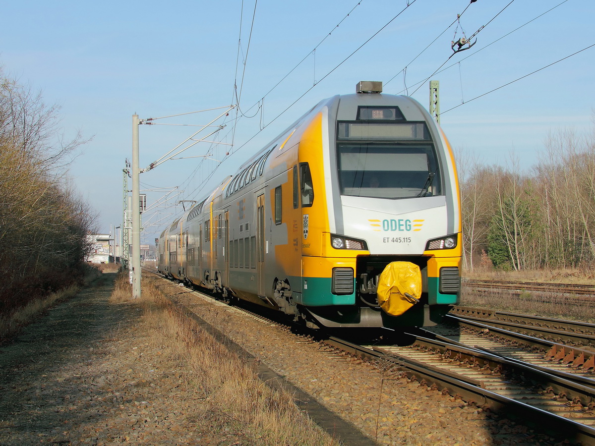 Königs Wusterhausen am 18. Januar 2014, soeben hat ET 445.115 der  ODEG - Ostdeutsche Eisenbahn GmbH als RE 83966 nach Cottbus den Bahnhof verlassen und den ersten Bahnübergang passiert.
 
 

