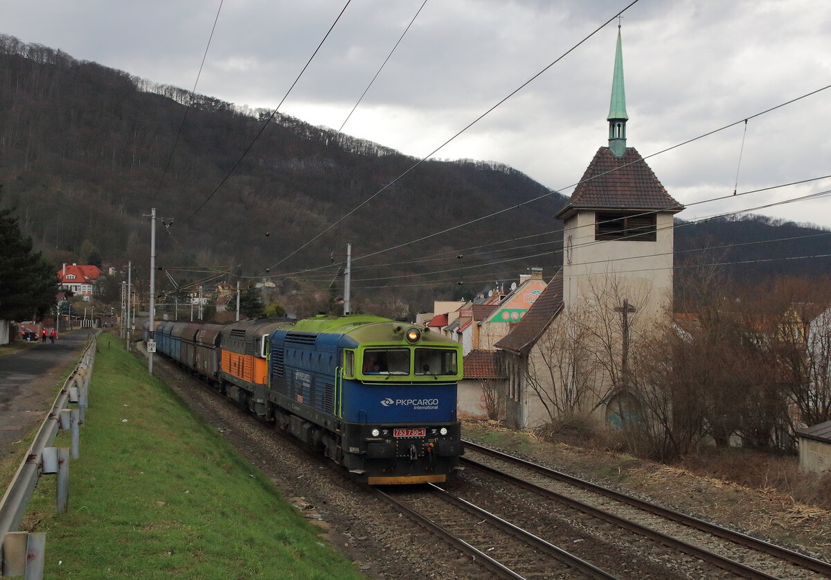 Kohlezug mit dem PKP Cargo Brillendoppel an der Kirche von Vanov vorbeifahrend in Richtung Kralupy. Die Führende, die 753 730 in leucht-grün blau und dahinter die 753 729 in grau orange lackiert. Aufgenommen am 20.3.2023 