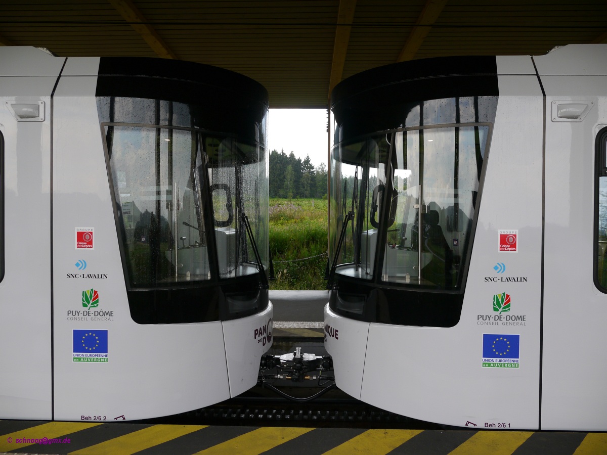 Kopf an Kopf: Beh 2/6 1 und 2 in der Talstation. 

Seit Mai 2012 fährt die neuerbaute Zahnradbahn Panoramique des Dômes zum Gipfel des Puy de Dôme.
Die 5,3 Kilometer lange Strecke führt von der Talstation (Maison de Site) zur Gipfelstation (Gare de Sommet) auf 1406 Meter Höhe. Die meterspurige Strecke hat Y-Stahlschwellen und eine Zahnstange nach System Strub. Die vier Triebwagen Beh 2/6 (Typ GTW) wurden von der Firma Stadler in der Schweiz gebaut.

Der 1465 Meter hohe Puy de Dôme ist ein Vulkangipfel, der die zu seinem Fuße liegende Großstadt Clermont-Ferrand um gut 1000 Meter überragt.


2014-07-26 Puy de Dôme

