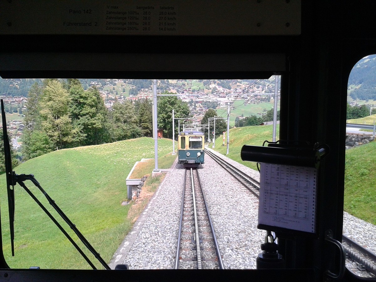 Kreuzungshalt zwischen Brandegg und Grindelwald Grund. Der Triebwagen dieser vorne zu sehen ist fuhr als Sonderzug für eine Reisegruppe nach Grindelwald Grund. Aufgenommen aus dem R 458 nach Grindelwald am 23.7.2015.