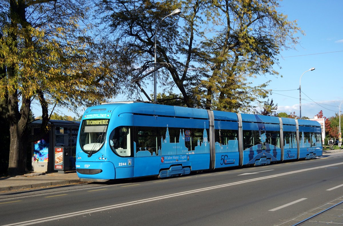 Kroatien / Straßenbahn Zagreb / Tramvaj Zagreb / Zagrebački Električni Tramvaj (ZET): CroTram TMK 2200 - Wagen 2244 (Werbung: 50 Jahre Städtepartnerschaft Mainz – Zagreb / 50. godišnjice prijateljstva Zagreba i Mainza), aufgenommen im Oktober 2017 an der Haltestelle  Ravnice  im Stadtgebiet von Zagreb.