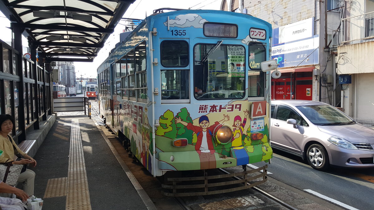 Kumamoto City Tram Typ 1350 Wagen 1355 an der Endhaltestelle Kengunmachi, 24.08.2016 
Der Wagen trägt hier Werbung der Toyota Niederlassung Kumamoto.

Die Firma Toyokouki baute 1960 6 Wagen des Typs 1350 für die Straßenbahn Kumamoto.
