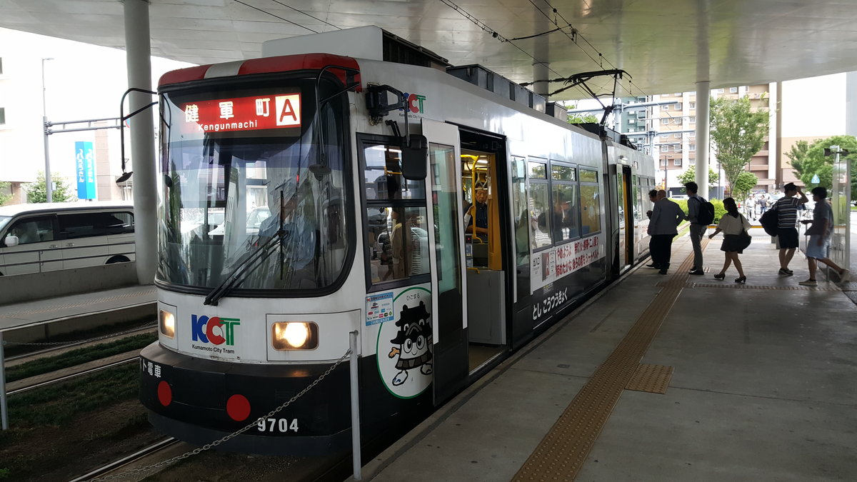 Kumamoto City Tram Typ 9700 Wagen 9702 am Bahnhof Kumamato, 24.08.2016

Wie nur unschwer zu erkennen ist handelt es sich beim Typ 9700 um eine Adtranz Niederflurstraßenbahn. Zwischen 1997 und 2001 baute Adtranz in Zusammenarbeit mit Niigata Transys insgesamt 5 Wagen in 3 Baulosen.
Die Lackierung soll an ein Polizeiauto erinnern und wirbt für Verkehrssicherheit.

