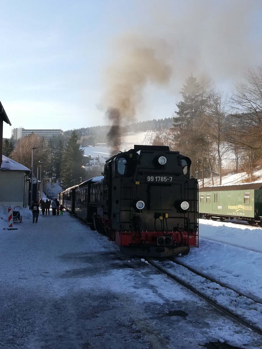 Kurort Oberwiesenthal hatte im Februar einiges an Schnee. Am 9.2. stand 99 1785-7 abfahrbereit vor dem Zug nach Cranzahl, vor dem Hintergrund des  Fichtelberges mit Skihang.