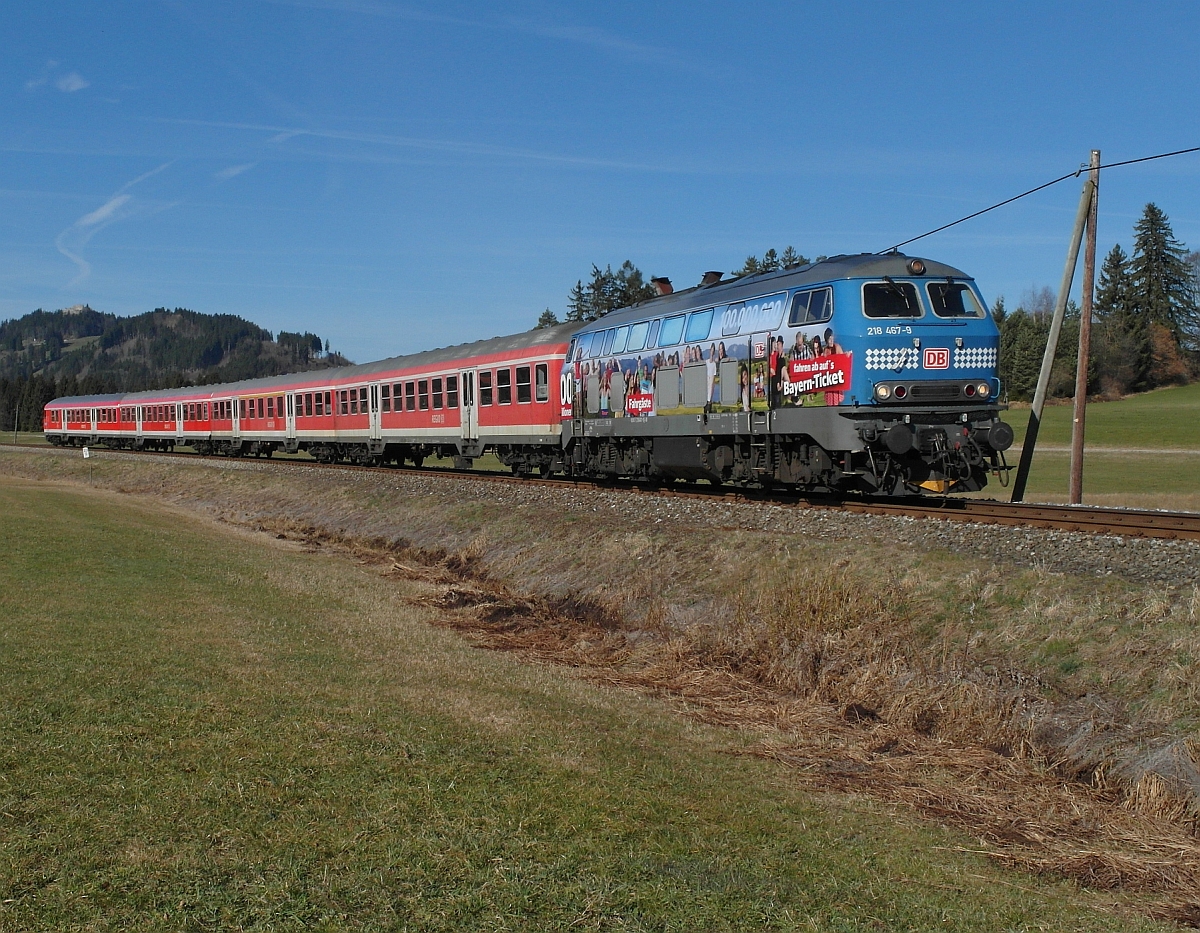 Kurz nach der Abfahrt an der Haltestelle Weizern-Hopferau umfährt 218 467-9 mit RE 57504 von München kommend die Ortschaft Hopferau und erreicht als nächstes den Zielbahnhof Füssen (18.03.2014).