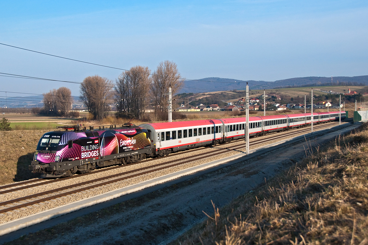 Kurz nach dem IC 740 kam der REX 1942 von Wien nach St. Valentin mit der neuen Werbelok 1116 170  Eurovision  im Tullnerfeld vorbei. Chorherrn, am 10.03.2015.