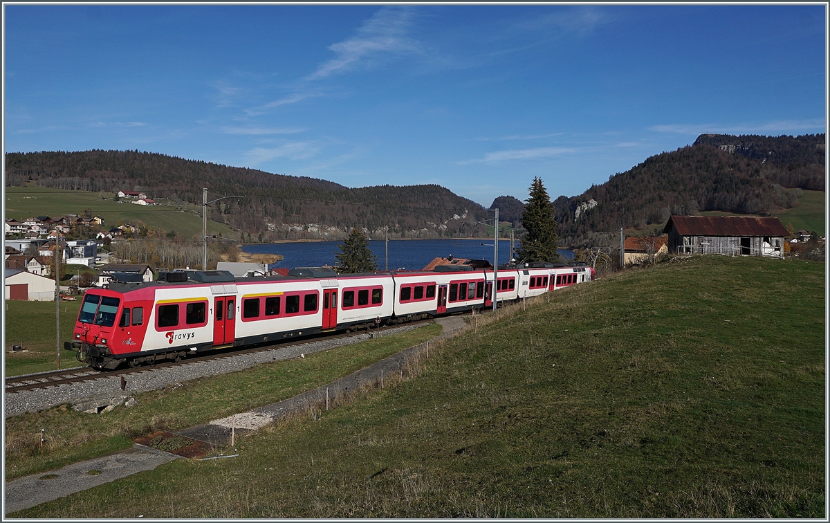 Kurz nach Les Charbonnières ist der TRAVY Regionalzug 6019 auf dem Weg nach Le Brassus. Der Zug besteht aus dem führenden Steuerwagen ABt NPZ DO TR 50 85 39-43 984-6 CH-TVYS, dem nachfolgenden Zwischenwagen B NPZ DO TR 50 85 29-43 384-1 CH-TVYS und dem schiebenden TRAVYS RBDe 560 384 (UIC RBDe 560 DO TR 94 7 560 384-0 CH-TVYS). Im Hintergrund ist der Lac Brenet zu erkennen. 

14. November 2020