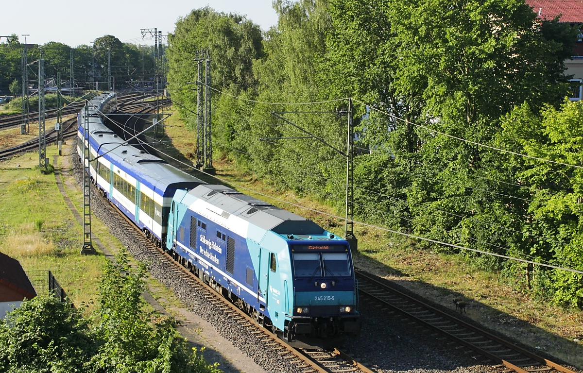 Kurz nach Verlassen des Bahnhofs Elmshorn befährt 245 215-9 mit dem RE 6 am Morgen des 08.07.2023 die ersten Meter der Marschbahn. Rund 2 1/2 Stunden später und 207 km weiter wird sie ihr Ziel Westerland auf der Insel Sylt erreichen.