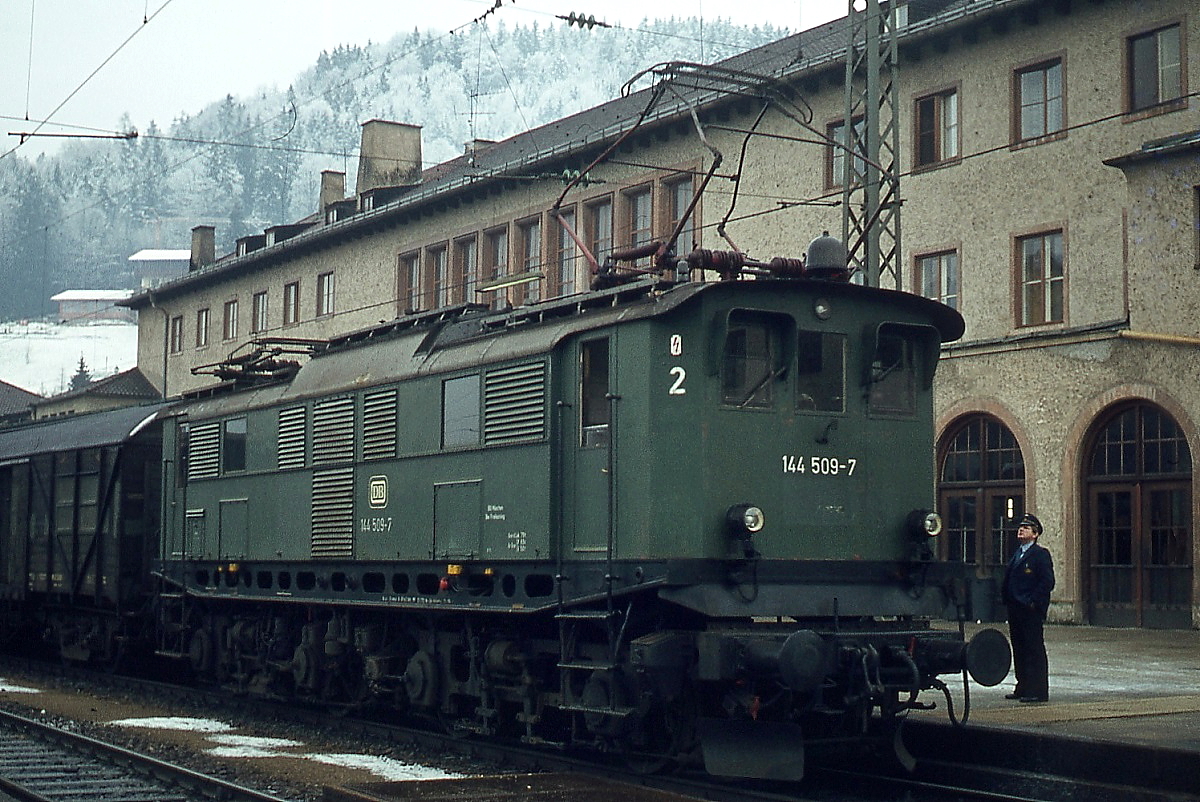 Kurz vor der Abfahrt ist noch Zeit für einen kurzen Plausch zwischen Schaffner und Lokführer der E 144 509-7. Das Foto entstand Ende Dezember 1977 im Bahnhof Berchtesgaden. Die E 44 506-509 unterschieden sich von den E 44 502-505 durch den trapezförmigen Brückenrahmen.