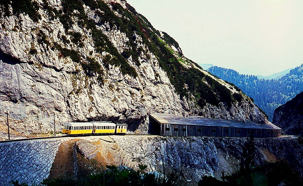Kurz vor der Bergstation hat ein Zug der Wendelsteinbahn im Sommer 1976 die Lawinengalerie passiert und fährt auf die Hohe Mauer