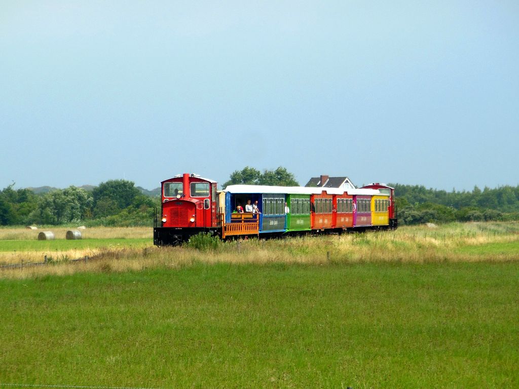 Kurz vor dem Anleger ist dieser Zug der Langeooger Inselbahn am 25.07.2015 unterwegs.