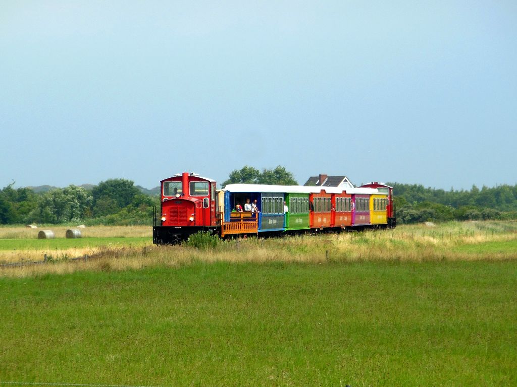 Kurz vor dem Anleger ist dieser Zug der Langeooger Inselbahn am 25.07.2015 unterwegs.