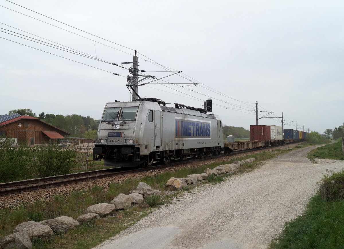 Kurz vor dem Bahnhof Hausleiten bei Stockerau ist die METRANS 386 037-6, der man ihren harten Einsatz ansieht, mit einem Containerzug Richtung Absdorf-Hippersdorf unterwegs, 26.04.2019.