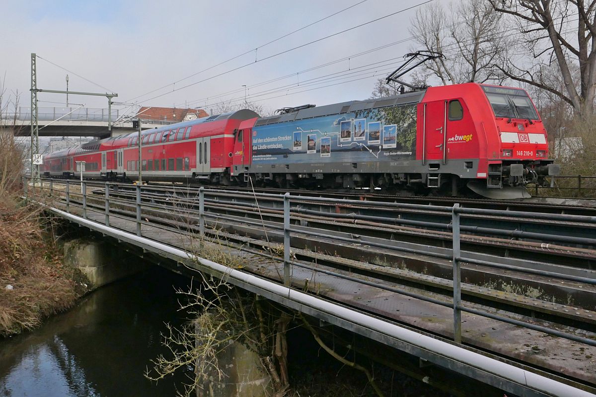 Kurz vor dem nchsten Halt in Biberach (Ri) schiebt die 'Bodensee-Lok' 146 210-0 am 26.01.2022 die Wagen des RE 5 /4216, Lindau-Reutin - Stuttgart ber den Rotbach, der hinter der Brcke in die Ri mndet