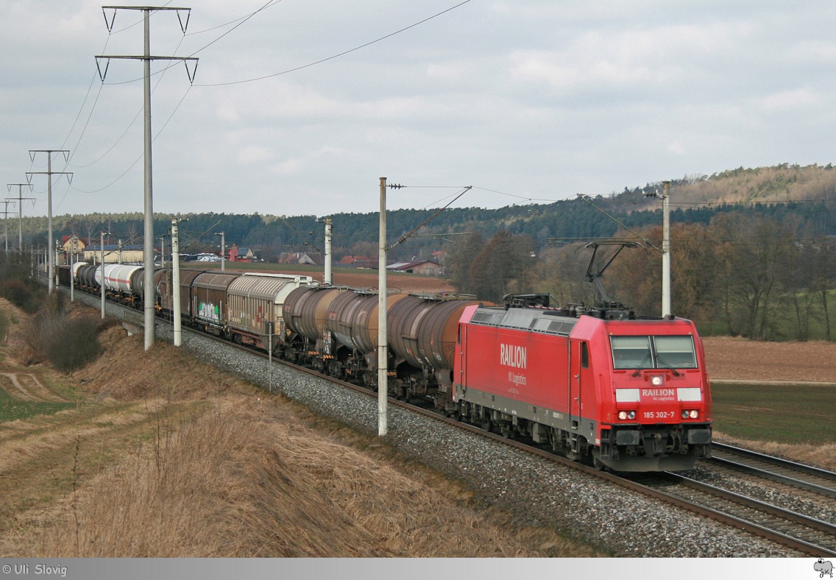 Kurz vor der Durchfahrt des Bahnhofes in Neustadt an der Aisch ist hier am 12. März 2015 185 302-7 mit ihren gemischten Güterzug zu sehen.