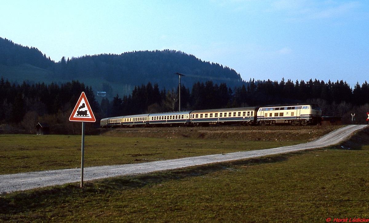 Kurz vor Oberstdorf ist eine unbekannte 218 mit einem typischen Epoche 4-Zug unterwegs (April 1982)